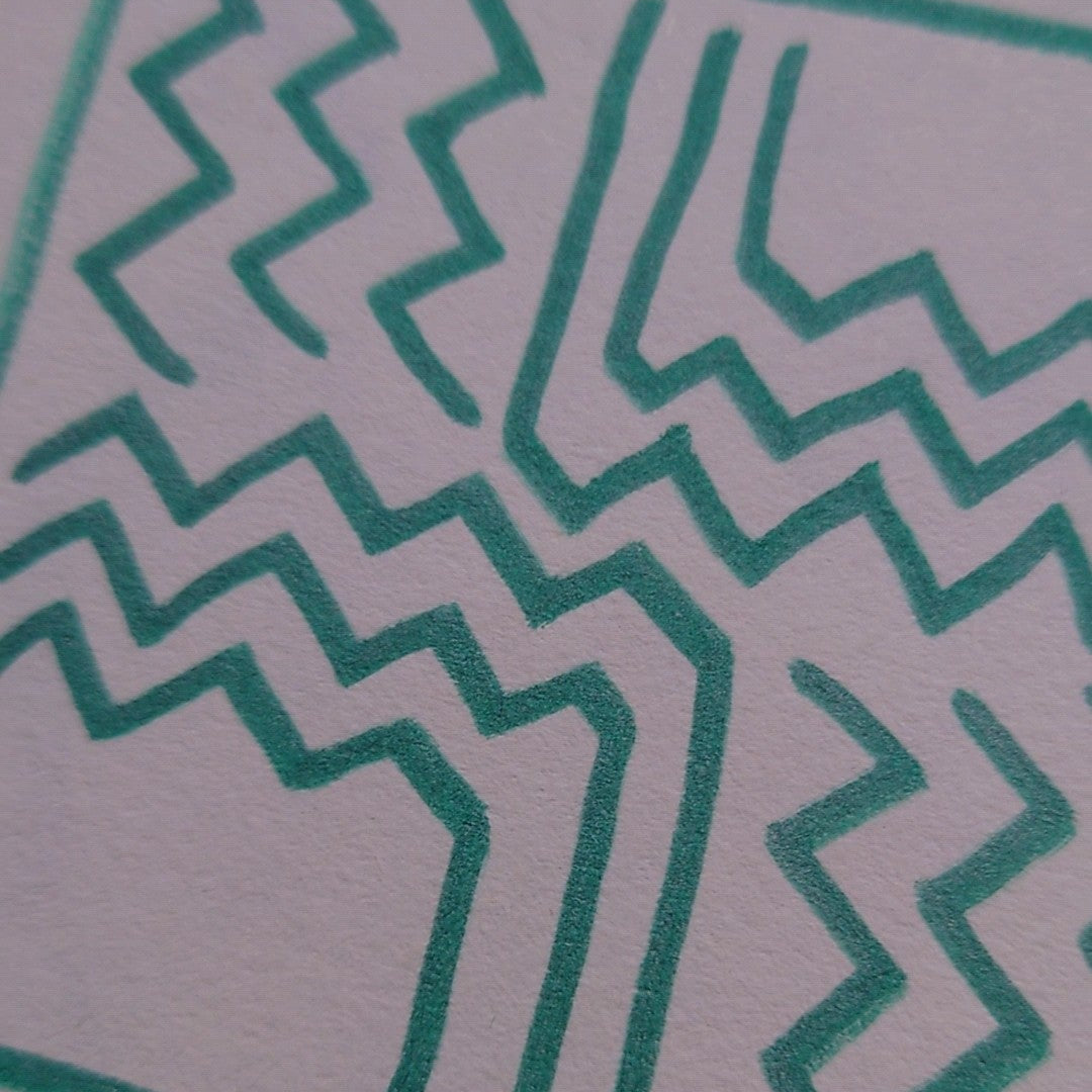 A close-up of a white textured surface with a repeating teal zigzag and maze-like line pattern.